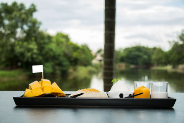 Mango sticky rice in a long black plate, blurred background