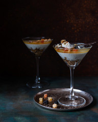 Mousse of cottage cheese with lemon layer, nuts and candied fruits in a high glass on a dark background. Close up. selective focus. The concept of Christmas and holiday. Healthy lifestyle.