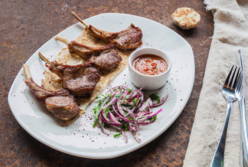 Pieces of t-Bone grilled steak with fresh cabbage and red onion salad on lavash and adzhika, served on a white plate on a stone countertop. Close up. Selective focus. Advertising and menu concept.