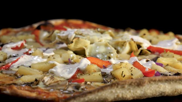 Sauce is poured over a rotating pizza in close-up