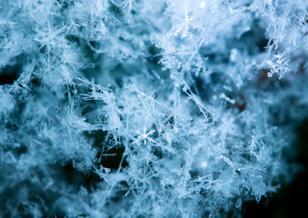 blue background of snow crystals of various shapes and textures lie and shimmer in the sun on a clear winter day