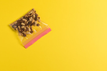 Plastic zip package for food storage. Healthy snack nuts in a closed package on yellow background