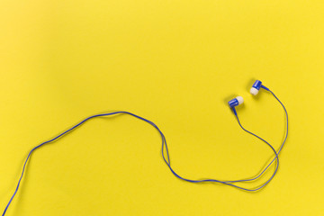 black earphones on colour background, top view