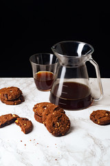 A pile of chocolate cookies with pour over coffee on marble table
