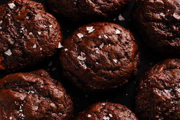 Top view image of soft chocolate cookies with salt flakes on dark background
