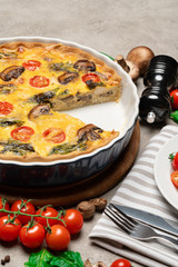 Baked homemade quiche pie in ceramic baking form and slice