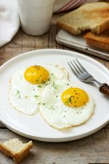 Breakfast of fried eggs, bread toasts and coffee on a wooden table. Rustic style.