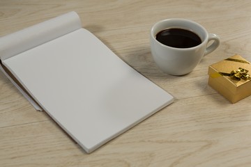 Fototapeta na wymiar Gift box, notepad and black coffee on wooden table