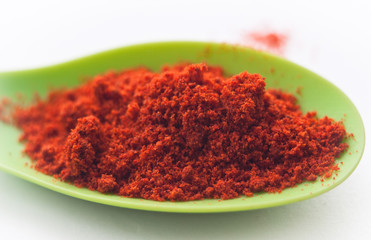 dry paprika in spoon. white background. close up