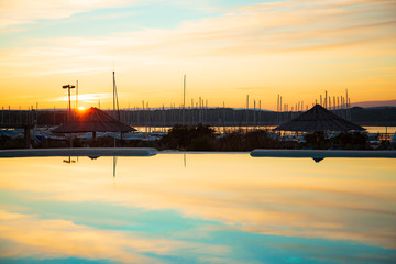 Sonnenuntergang, im Vorderund ein Hafen, Schiffe, Marina