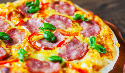 Pizza with Mozzarella cheese, ham, pepper, meat, Tomato sauce, Spices and Fresh Basil. Italian pizza on wooden background