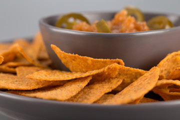 Close-up nachos on a plate with hot sauce. Mexican appetizer.