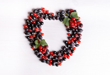 Black gooseberries blackcurrants and redcurrants. Fresh summer berries on white table. Top view. Flat lay.