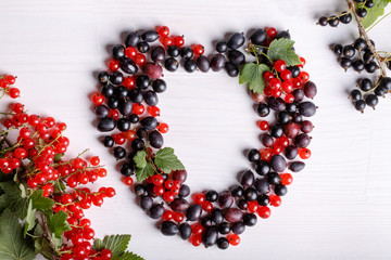 Black gooseberries blackcurrants and redcurrants. Fresh summer berries on white table. Top view. Flat lay.