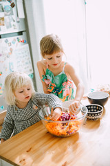 Two sisters making a healthy salad at the kitchen