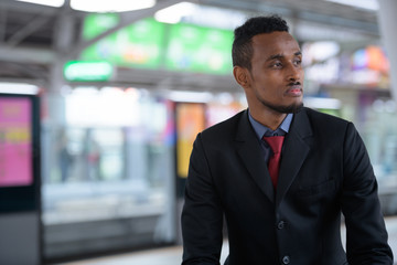 Young African businessman thinking while waiting at the train station