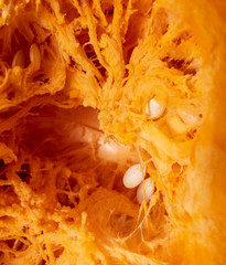 Orange pulp with seeds in a pumpkin as background