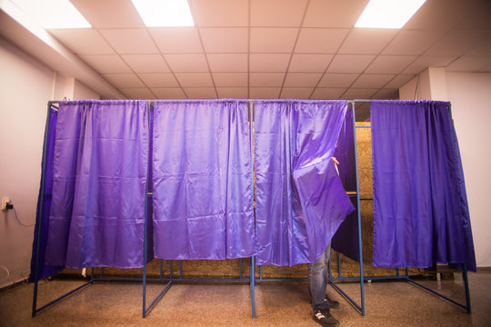 Person voting in booths at a polling station