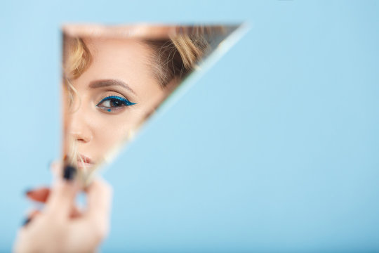 Fototapeta Woman looking at her self reflected in a mirror, selfie, vanity, conceit, ego, digital narcissism concept minimal flat design. An illusion, beautiful girl with a mirror in her hands
