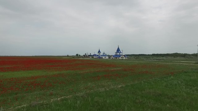 Church in the field. Spring green field, red poppies. Video from the air. Kazakhstan.