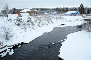 Snowy winter landscape with river and village houses
