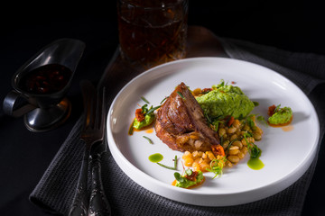 A braised lamb shoulder with mashed broccoli and some roasted beans