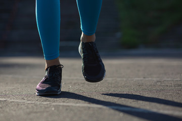 Athlete woman feet during jogging workout on the stadium. Empty space