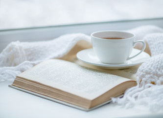 Écharpe chaude en tricot, une tasse de thé chaud et un livre