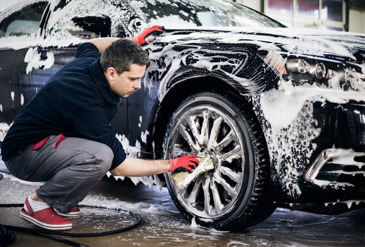 Man Worker Washing Car's Alloy Wheels On A Car Wash