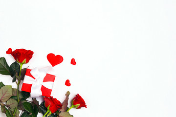 Gift box, rose flowers and decorative hearts on white background. Place for text, top down composition.