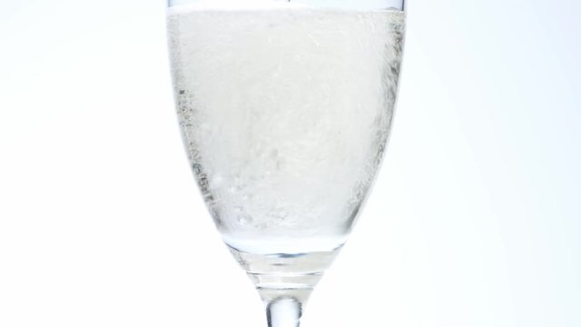 白い背景でグラスにシャンパンを注ぐ