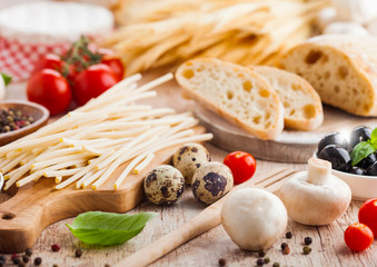 Homemade wheat bread with quail eggs and raw wheat and fresh tomatoes on wooden background. Classic italian village food. Garlic, black and green olives. Wooden spatula