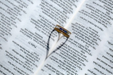 Wedding Ring and heart shaped shadow over a Bible