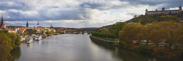 Panorama of the Main in Würzburg in autumn. In the picture are the banks of the river, the old town and its historic buildings and the old fortress towers over the city. a dramatic sky at sunset.