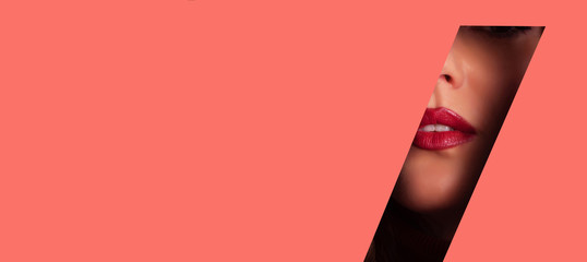 Girl with bright make up, red lipstick looking through hole in living coral paper. Make up artist, beauty concept. Ready to party. Cosmetics sale. Beauty salon advertising banner with copy space