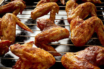 Delicious hot grilled chicken wings on grid grill.