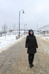 The woman costs one on the road near streetlights in the winter