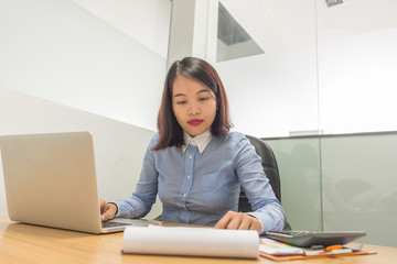 Female manager reading financial report and working with laptop