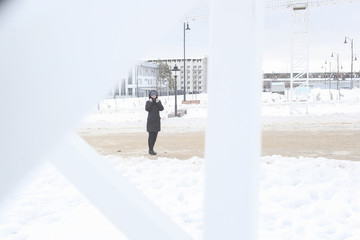 Portrait of the freezing woman in the winter through a white frame of city designs. A portrait on a belt