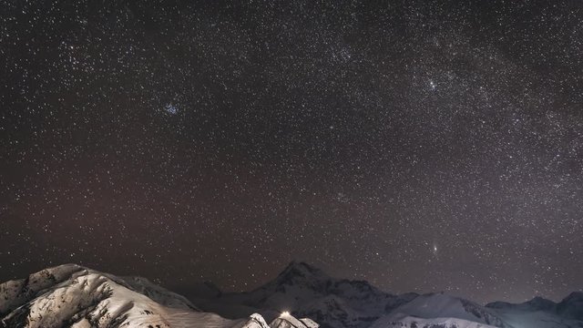 Stepantsminda, Georgia. Winter Night Starry Sky With Glowing Stars Over Peak Of Mount Kazbek Covered With Snow. Beautiful Night Georgian Winter Landscape