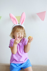Happy Easter. Lovely girls with ears of rabbits paint eggs.
