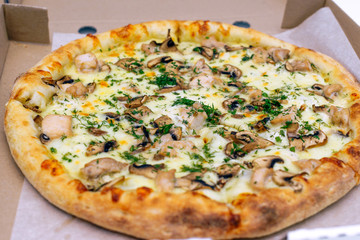 Pizza in a cardboard box on a light background. Top view. Pizza delivery. Pizza menu. Pizza on the kitchen table.
