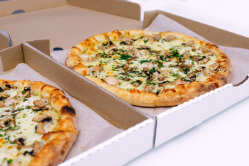 Two pizzas in a cardboard box on a light background. Top view. Pizza delivery. Pizza menu. Pizza on the kitchen table.
