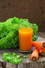 Carrot juice with greens on a wooden board