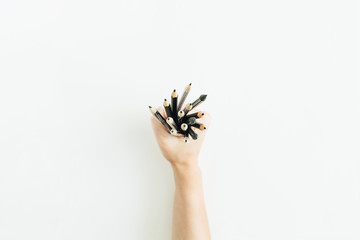 Woman hand holding bunch of pencils on white background. Flat lay, top view minimal artist composition.
