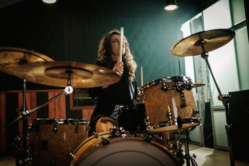 Woman playing drums during music band rehearsal