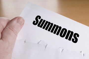 hand holding summons letter, unrecognizable person is summoned to appear in court