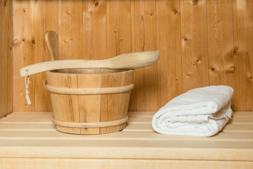 Fototapeta na wymiar Sauna cabin ready for usage with wooden bucket with wooden spoon and white towel