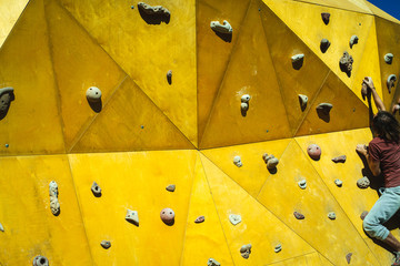 Athlete man trying to reach the top of a climbing wall with the strength of his hands and legs.