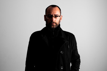 Unretouched portrait of serious bald middle-aged man with black coat.